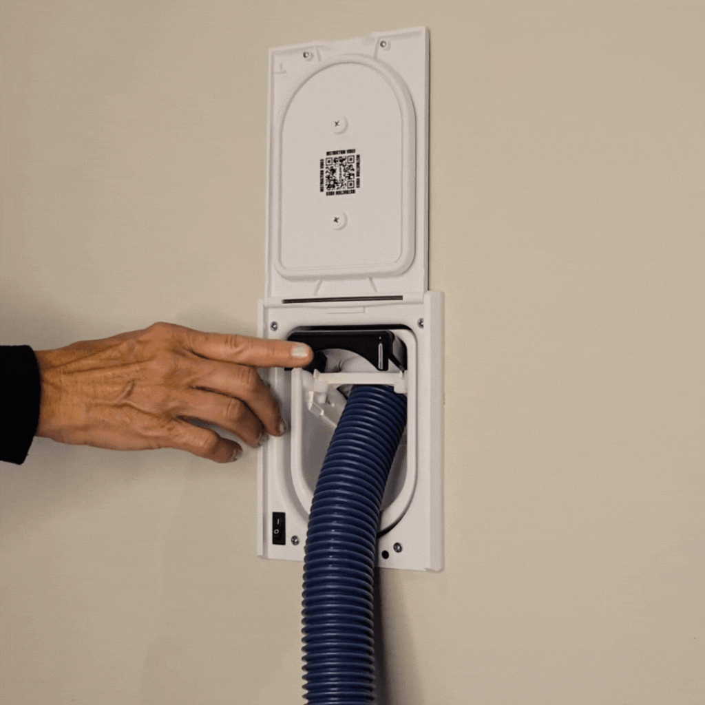 Person's hand pushing a button to retract a central vacuum system hose.