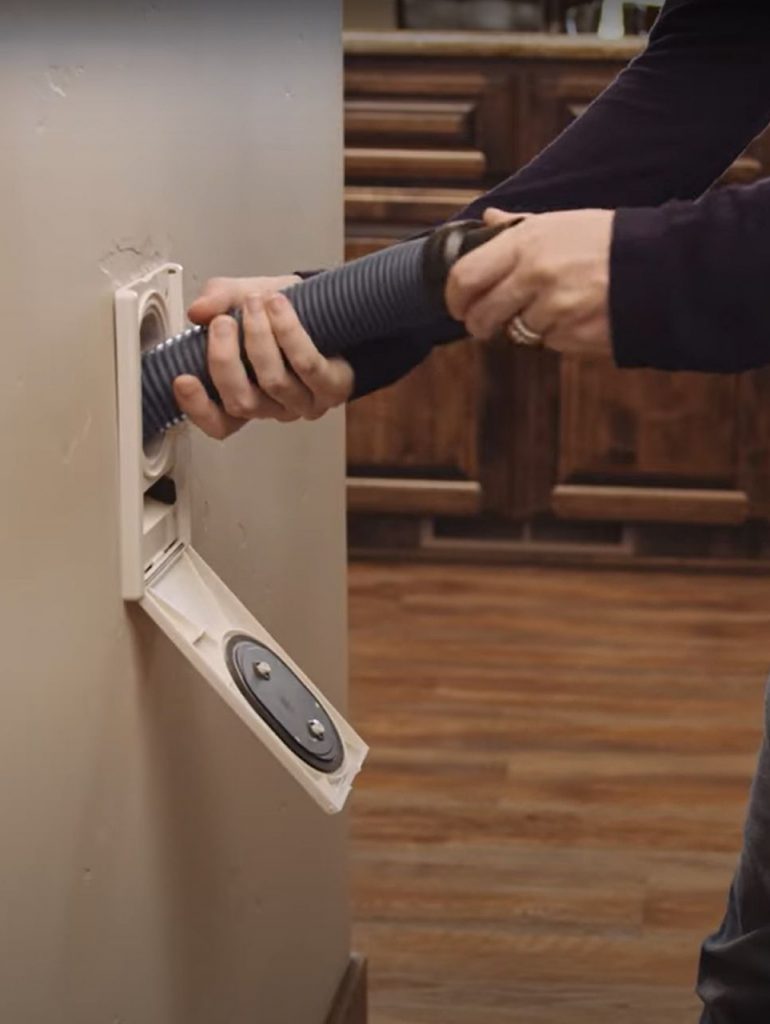 Image of a woman using the Hide A Hose accessory with their premier central vac system.
