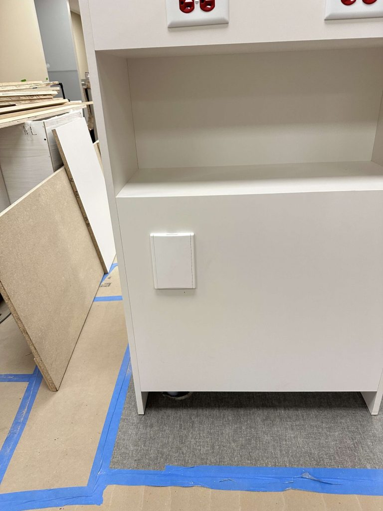 White central vacuum wall inlet built into the side of a clinic cabinet.