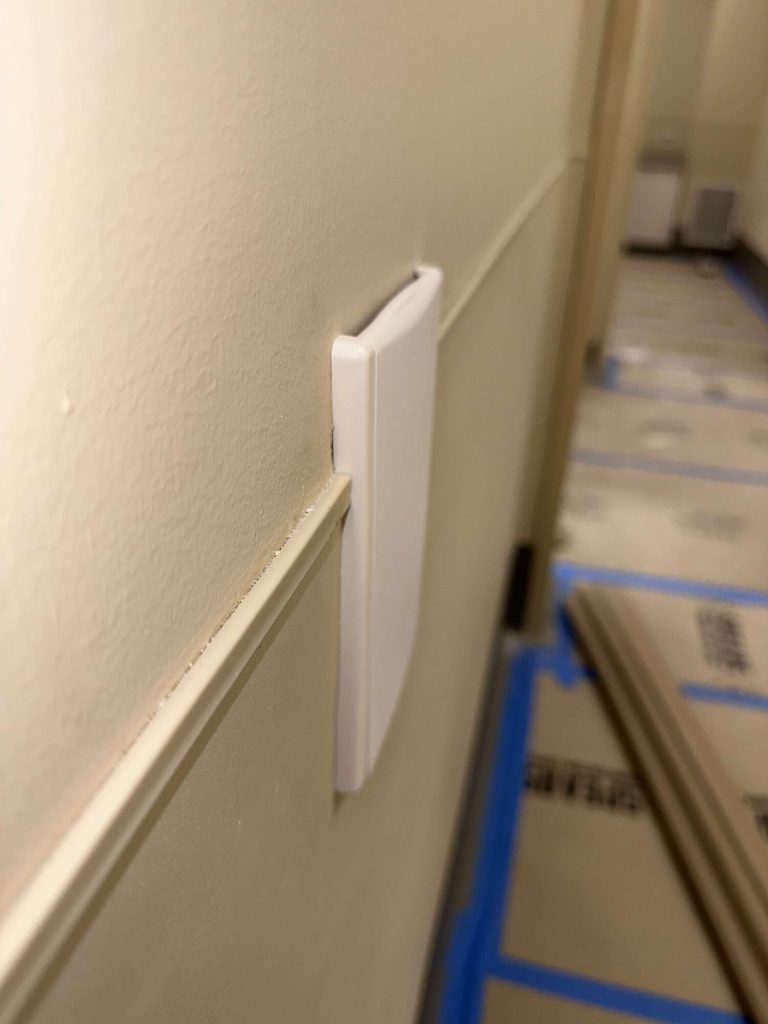 White central vacuum wall inlet installed in a clinic hallway.