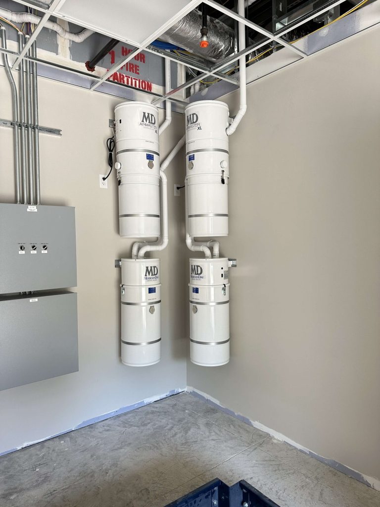 Two pairs of MD central vacuum power units installed side by side in a commercial mechanical room.